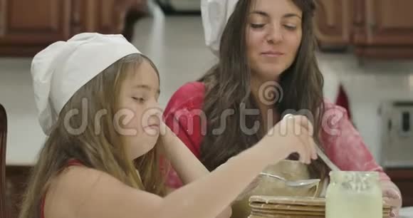 可爱的白种人小女孩和她开朗的妈妈一起吃着甜的浓缩米尔特母女幸福视频的预览图