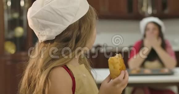 小白种人daughtr回头看她妈妈转向相机咀嚼甜烤饼干小可爱女孩视频的预览图