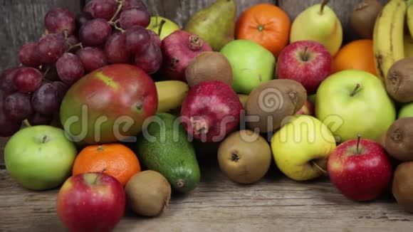 一套不同的水果放在木制的餐桌上香蕉芒果苹果鳄梨猕猴桃石榴橘子橘子梨视频的预览图