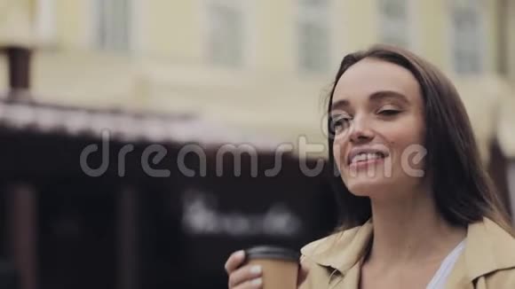 年轻漂亮的快乐女孩的肖像喝着咖啡微笑着走着轻松的古城背景结束了缓慢的运动视频的预览图