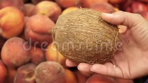 在新鲜桃子的背景下雌性手中的椰子视频的预览图