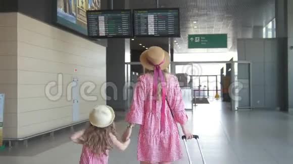 年轻母亲和可爱女儿在机场牵手观看航班时刻表的后景视频的预览图
