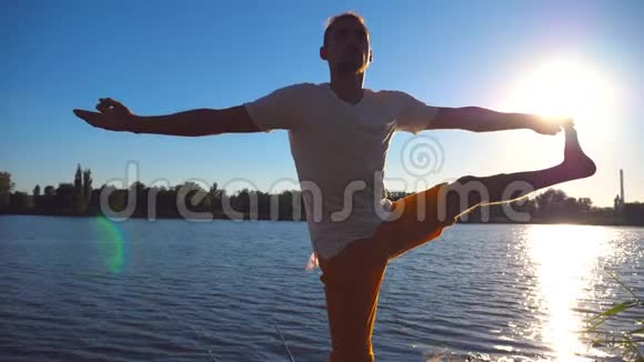 站在瑜伽馆前的年轻人在湖边的木制码头摆姿势运动员在大自然中单腿平衡体育界的家伙视频的预览图