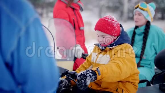 冬季森林一个小男孩坐在雪地车上拧着煤气手柄视频的预览图