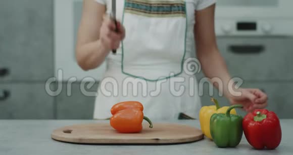 在现代厨房的视频中一个女人在镜头前剪了一个橙色的甜椒特写4k视频的预览图