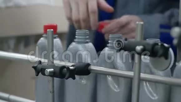 工厂工人的手关闭灰色塑料瓶上的盖子移动在室内的传送带上视频的预览图