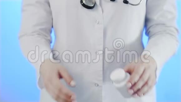 医生用蓝色背景从瓶子里倒出一粒黄色药丸视频的预览图