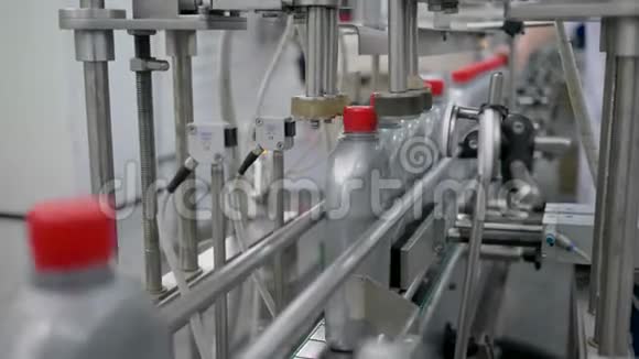 生产电机油的工厂自动机器将红帽固定在输送机上的塑料瓶上视频的预览图