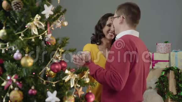 可爱的一对情侣在美丽的圣诞树旁慢慢跳舞庆祝新年视频的预览图