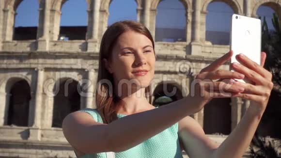 女人在意大利罗马竞技场附近的手机上自拍少女在慢动作中微笑视频的预览图