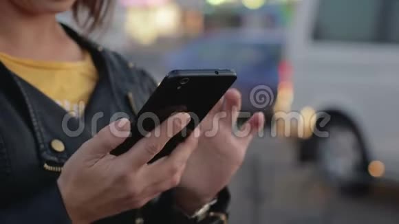 一位年轻女孩的肖像她站在城市里手里拿着一部智能手机和手机视频的预览图