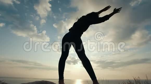 日出时在悬崖上做斜坡的女性剪影视频的预览图