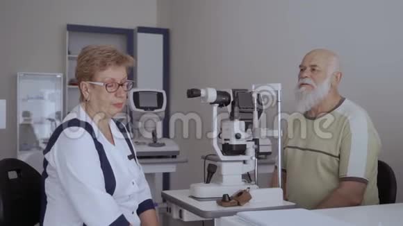 眼科医生在检查了老病人的视力后与他交谈视频的预览图