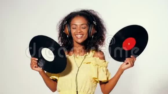年轻美丽的非洲裔美国女性戴着黄色的耳机穿着白色的黑胶唱片尽情地跳舞视频的预览图