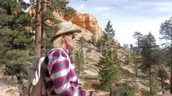 布莱斯峡谷岩石和松树中一位徒步女徒步前行的侧景视频的预览图