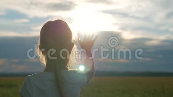 金发小女孩用手看太阳田野里日落时一个孩子的剪影视频的预览图