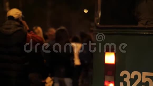 在夜间道路上移动的抗议人群背景下的紧急汽车警示灯视频的预览图