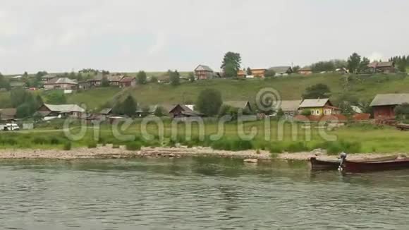 古老的俄罗斯村庄有古老的木屋乡村道路和绿色多汁的草地在小河边视频的预览图