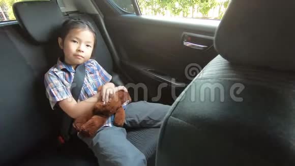 快乐的小女孩戴着安全带在车里拿着智能手机视频的预览图