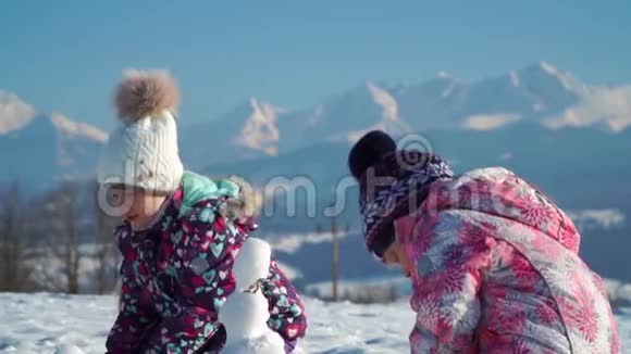 穿着户外服装的快乐的小女孩在阳光下站在户外撒雪视频的预览图