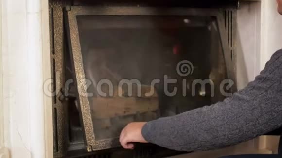 4k视频年轻人打开壁炉玻璃门把木头放进去视频的预览图