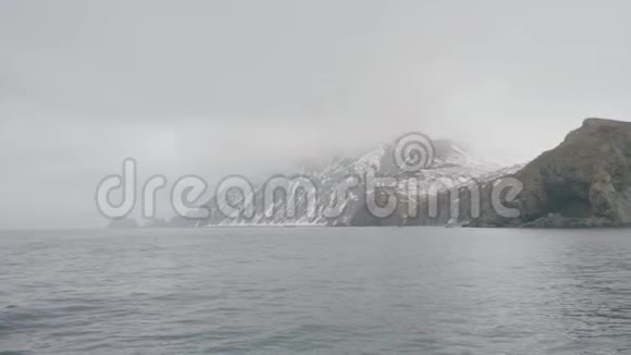 在雾蒙蒙的海洋中的雪山和悬崖视频的预览图