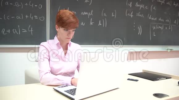 年轻女子在课堂上用电脑准备教学课视频的预览图