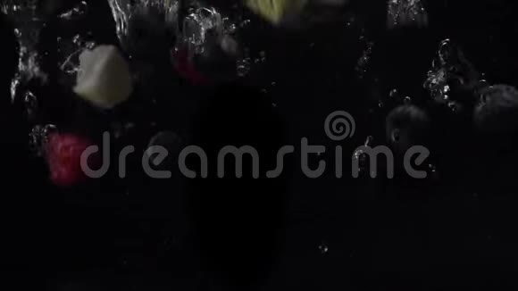 蓝莓蓝莓黑莓和苹果碎片在黑色背景下落入水中慢动作有机有机视频的预览图
