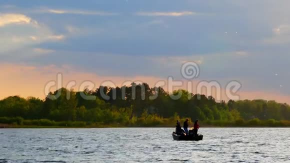 日落时分在湖上渔船上的渔民剪影视频的预览图