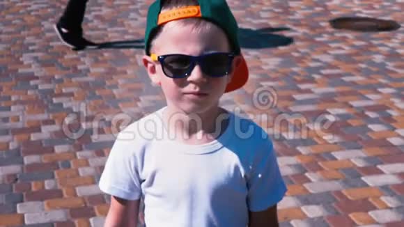 戴着太阳镜戴着帽子的小男孩走在街上6岁的孩子走着慢动作视频的预览图