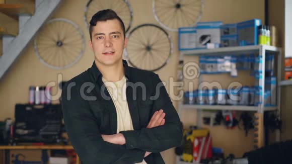 自行车修理车间老板站在他的工作场所看相机的肖像自行车备件修理视频的预览图