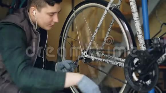 年轻的自行车修理师傅正在用扳手和旋转轮调整车轮机构以检查工作质量周期视频的预览图