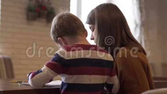 一个迷人的年轻母亲和儿子坐在餐桌前视频的预览图