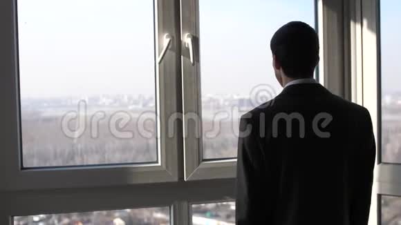 年轻的成功商人站在窗前眺望城市的远方慢动作视频的预览图