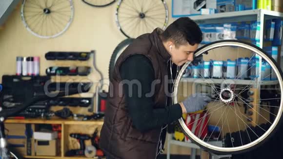 年轻的军人正在用工具和一块布清洁自行车轮用音乐倾听视频的预览图