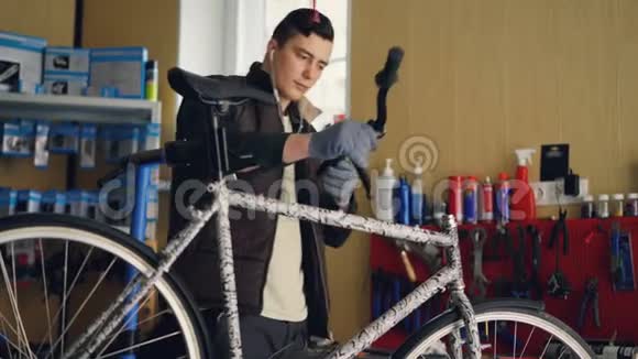 专注的机械师正在组装自行车放置车把然后用钥匙拧紧接头通过听音乐视频的预览图