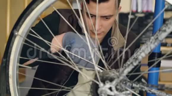 专心致志的人熟练的机械师在工作场所工作时用扳手修理自行车车轮自行车维修视频的预览图