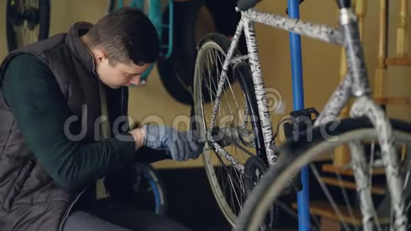 戴着手套的英俊男军人正在用专业工具修理自行车后轮自行车备件和视频的预览图