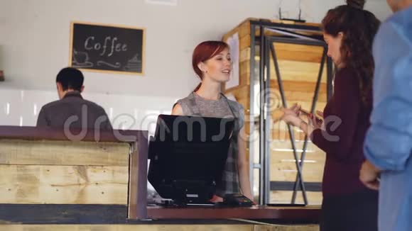 在舒适的咖啡屋忙碌的工作一天顾客们站在柜台边用智能手机付款买咖啡视频的预览图