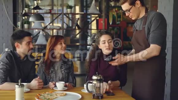 年轻漂亮的女人在和朋友一起吃午饭后用智能手机在咖啡馆吃饭现代技术无接触视频的预览图