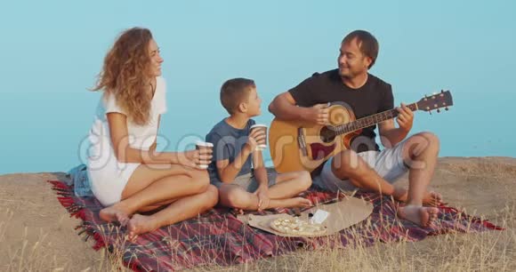 一家人晚上坐在海滩边弹吉他视频的预览图