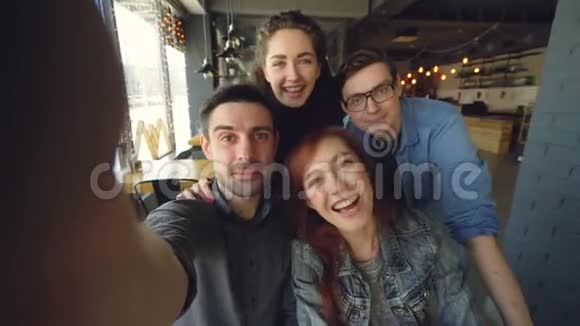 一群快乐的朋友在咖啡馆里拍了一段有趣的视频摆姿势微笑着拥抱和手势视频的预览图