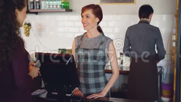 咖啡馆的工作人员热情地向顾客打招呼用智能手机支付银行卡终端和视频的预览图