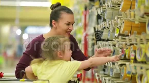 在超市里微笑的母亲和女儿女儿帮助母亲选择一种胶带可爱的女儿视频的预览图