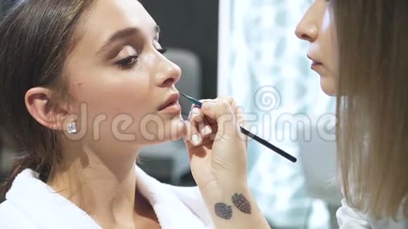 专业女性在女士嘴唇上涂化妆品视频的预览图
