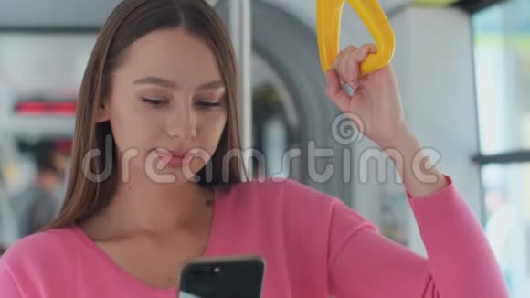 一位年轻女子站在现代电车上用智能手机拍摄的特写照片视频的预览图