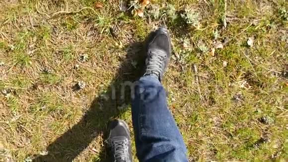 一个穿着牛仔裤和运动鞋的人的腿在草地上缓慢地行走视频的预览图