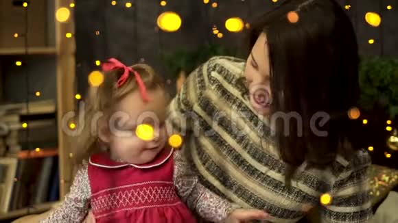 年轻的迷人的微笑的女人妈妈带着一个快乐的甜美的孩子在黄色后面的美丽的新年工作室里视频的预览图