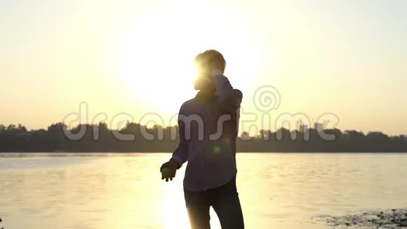 夕阳西下年轻人站在河岸上视频的预览图