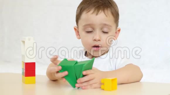 一个孩子正在用彩色积木玩耍坐在白色背景的桌子旁孩子和玩具聚焦相机的目标是视频的预览图